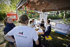 An einem Stand mit Wimpeln stehen eine Frau und ein Mann.