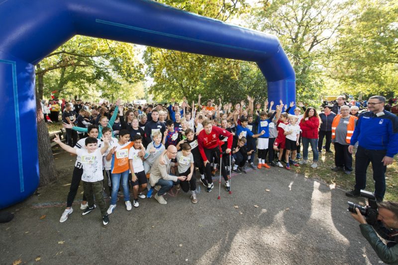 Eine sehr große Menschen-Gruppe steht unter einem blauen Luftbogen.