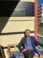 Eine Person mit dem Buch "Fackel der Angst. Von Homs nach Magdeburg." in der Hand.