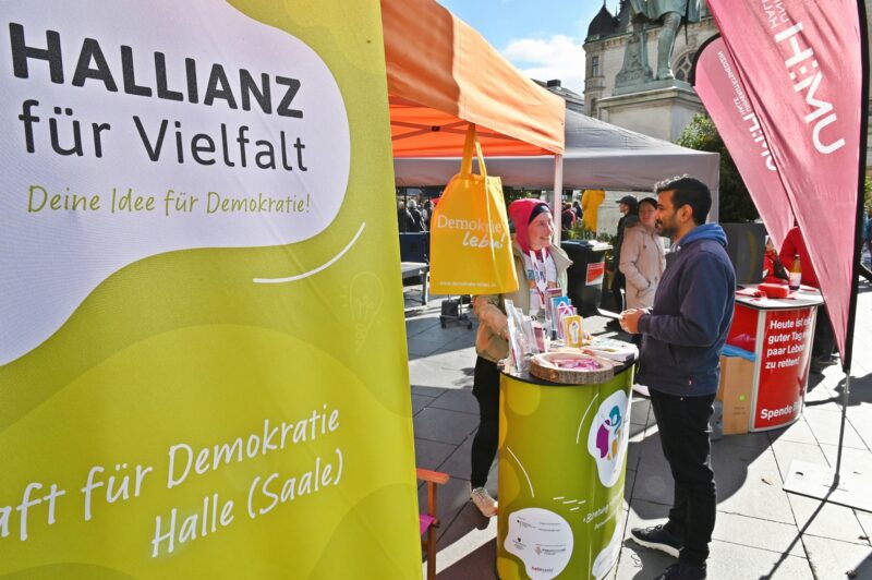 Zwei Personen stehen an einem Info-Stand und unterhalten sich.