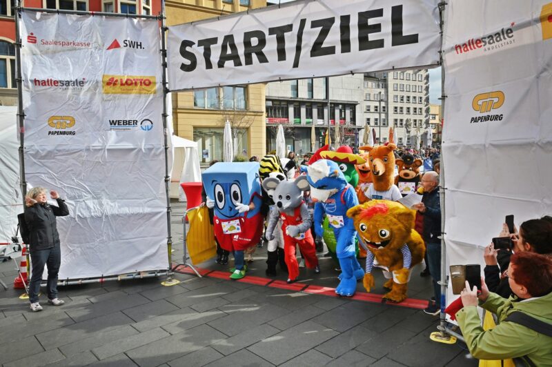 Eine Gruppe Maskottchen steht an einer Startlinie und ist bereit loszulaufen.